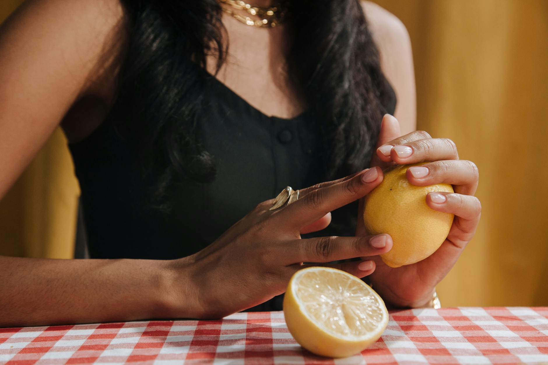 Close-up of a hand holding an orange vibrator against a minimalistic purple backdrop, showcasing modern sensuality.