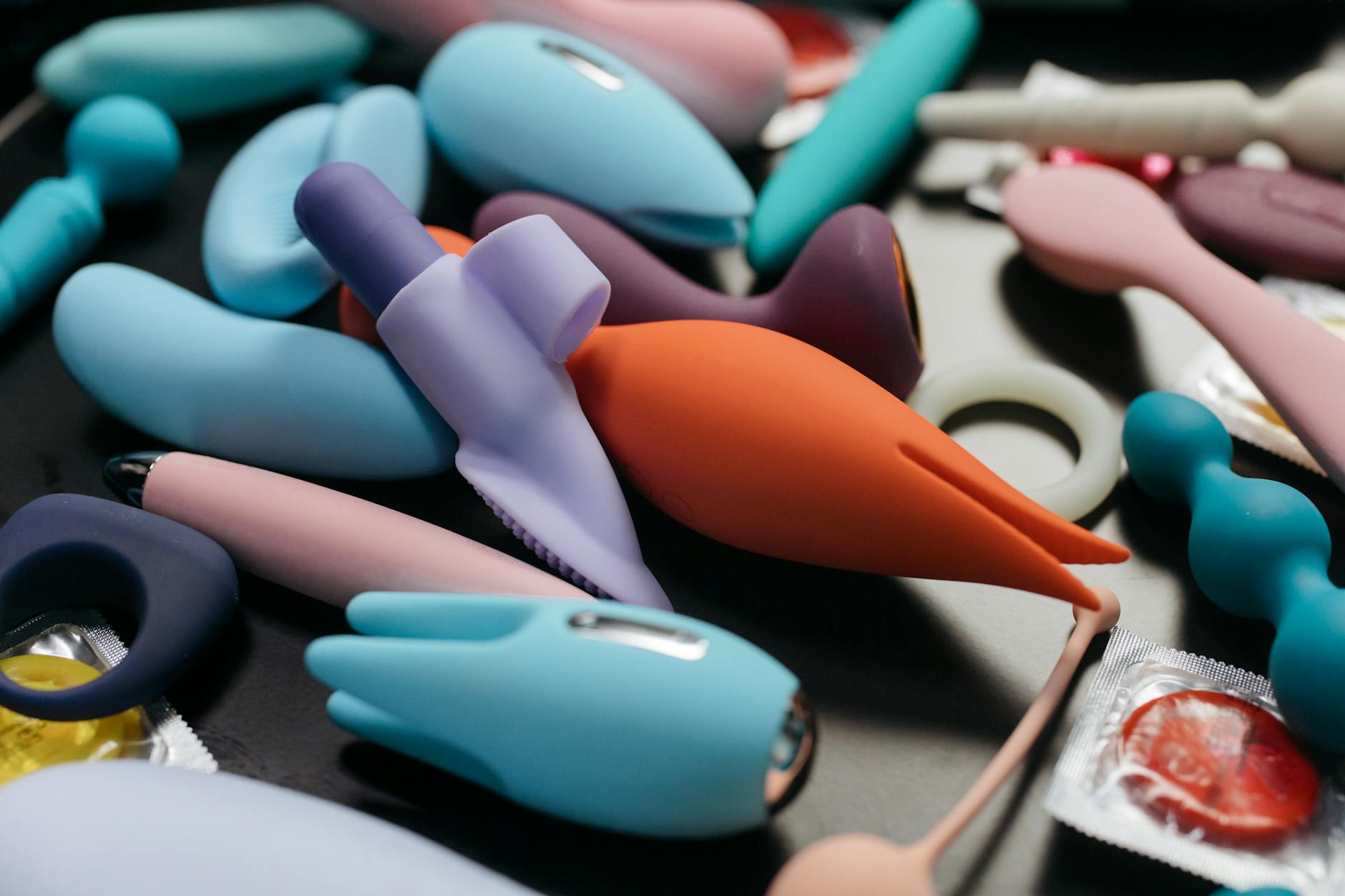 A hand holding a blue silicone clitoral vibrator against a purple background, representing self-discovery and pleasure during healing