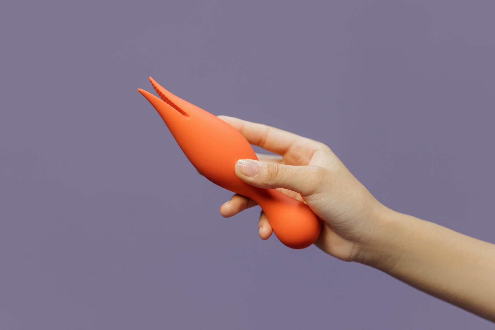 Close-up of a hand holding a lemon vibrator against a minimalist purple backdrop, representing sensual reconnection.