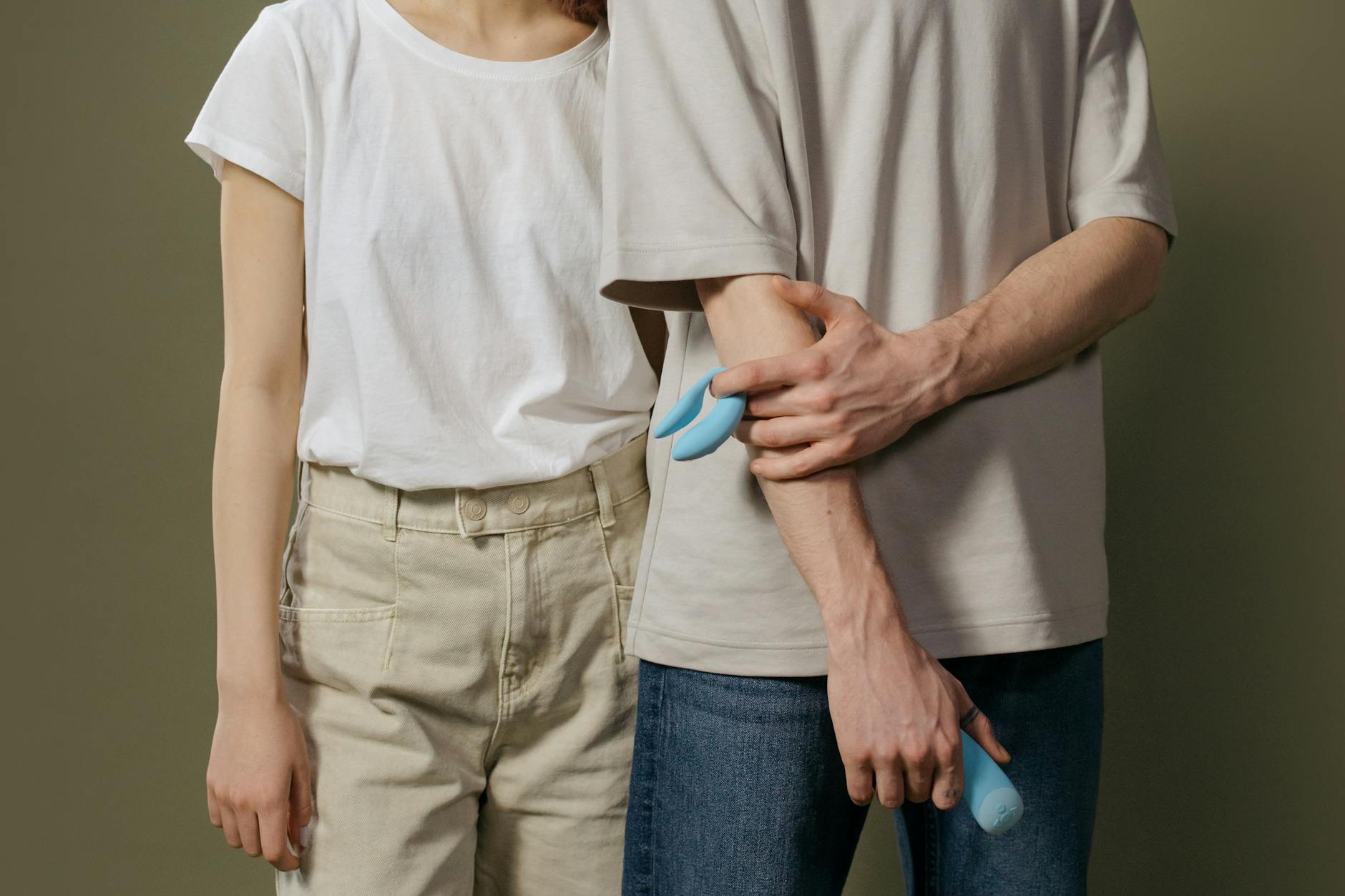 A couple standing together, holding a blue vibrator, exploring intimacy and trust with modern tools.