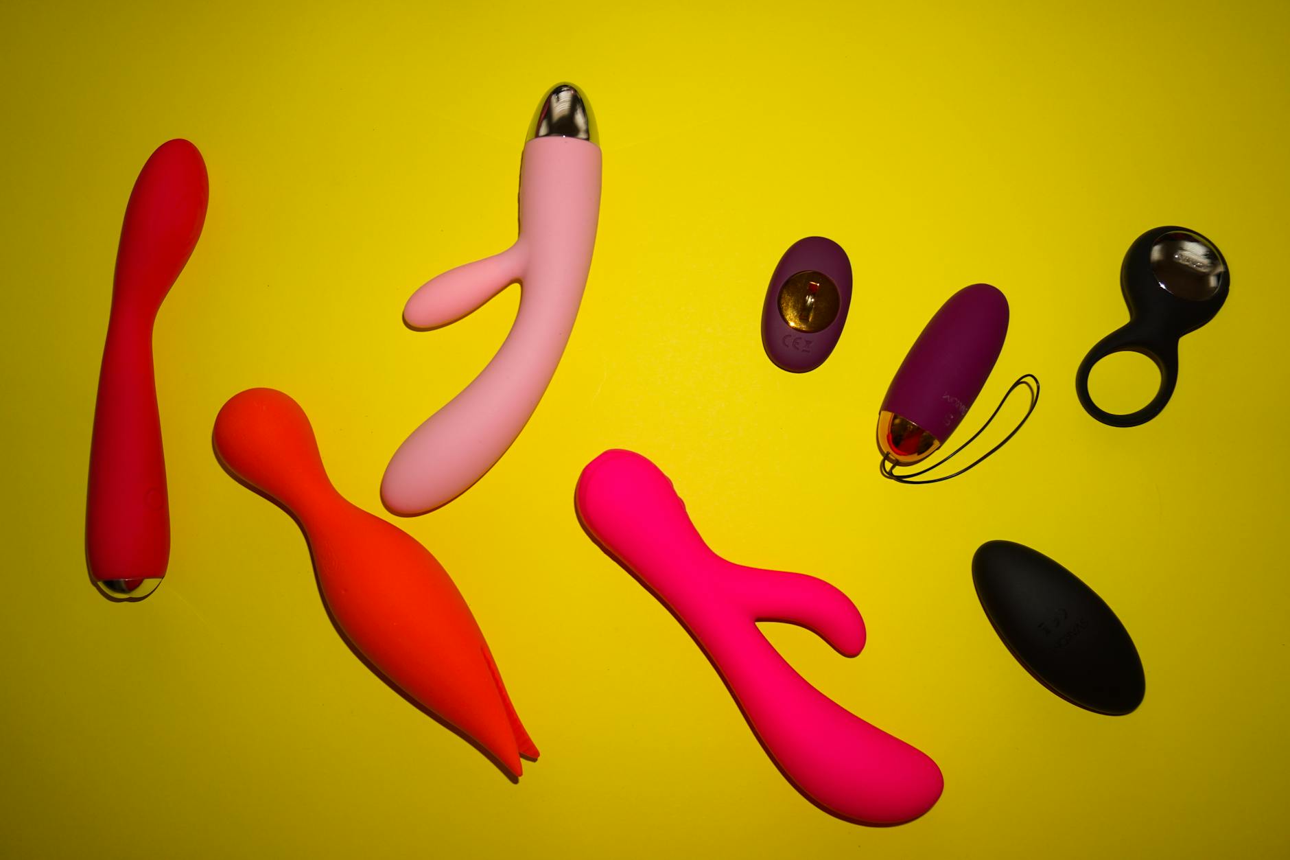 Variety of colorful lemon vibrators and adult toys displayed on a bright yellow surface