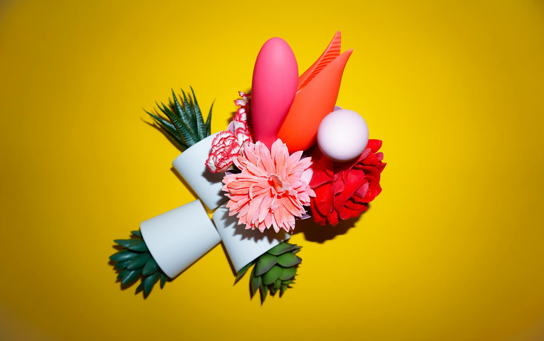 Person holding two colorful vibrators against a purple background, exploring pleasure options.
