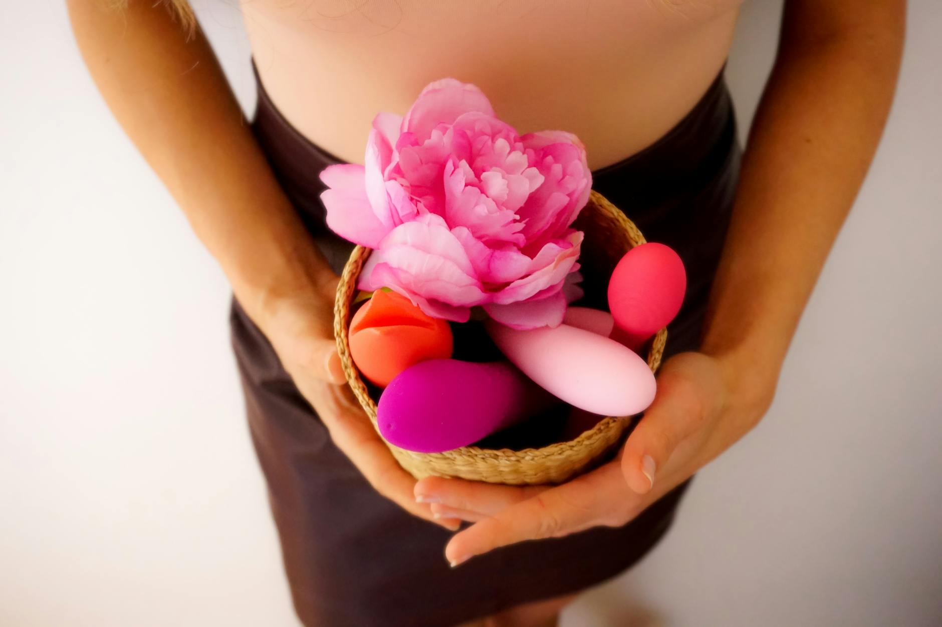 Close-up of hands holding a sleek lemon clitoral vibrator against a soft purple background