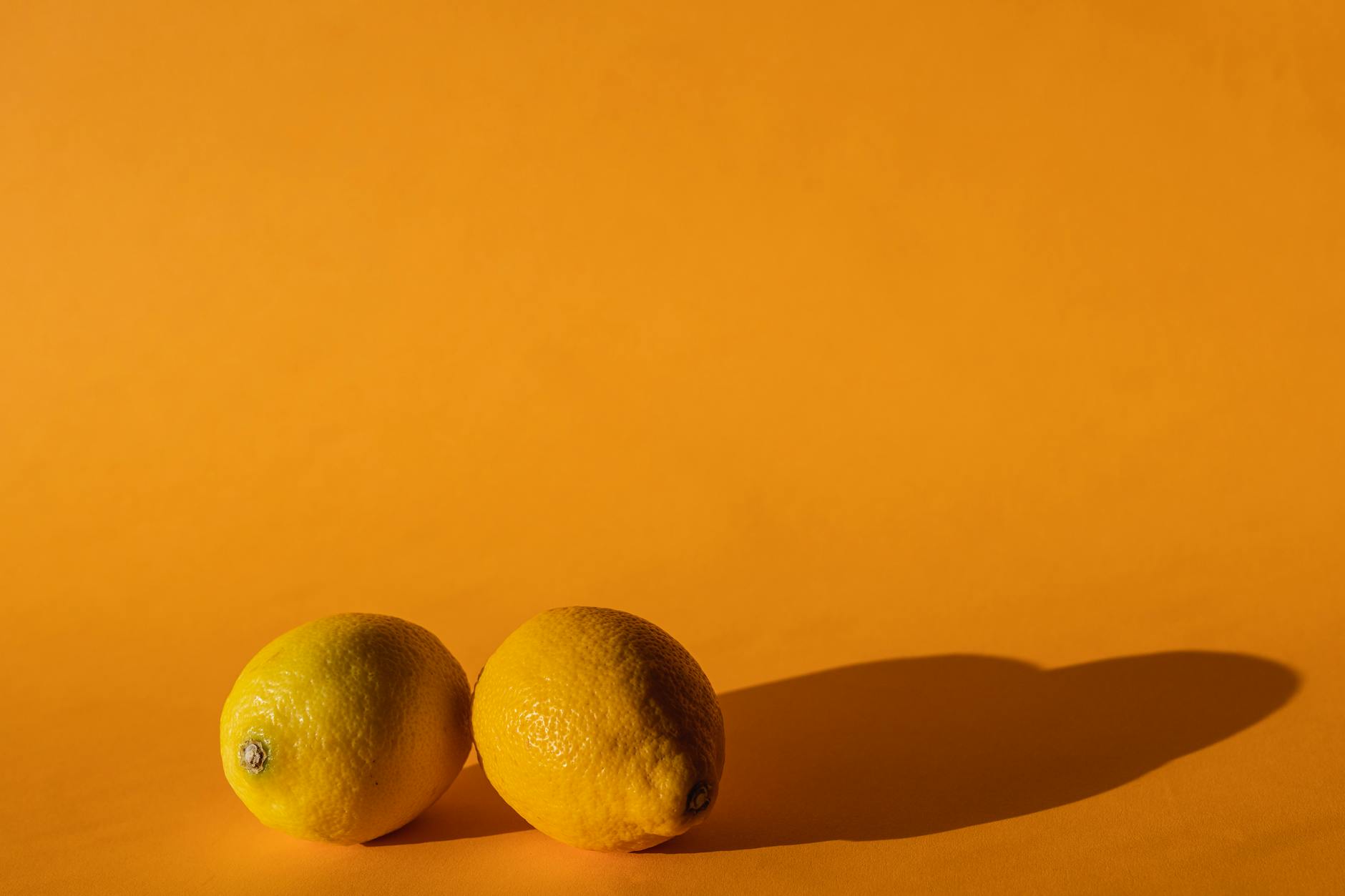 Hand holding a lemon clitoral vibrator against a purple backdrop